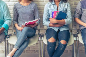 Group of international college students sitting in chairs holding notebooks