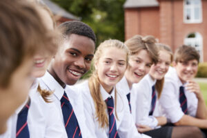 Group of boarding school students In uniform outside school buildings