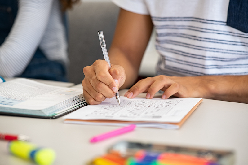 High school student filling out test answers with pencil