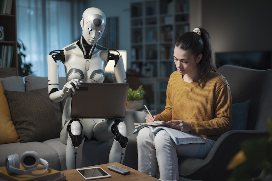 A young woman and her AI android study together on a couch, representing the future of artificial intelligence.