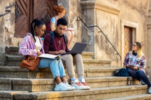 A diverse group of students sitting on stairs talking and learning together.