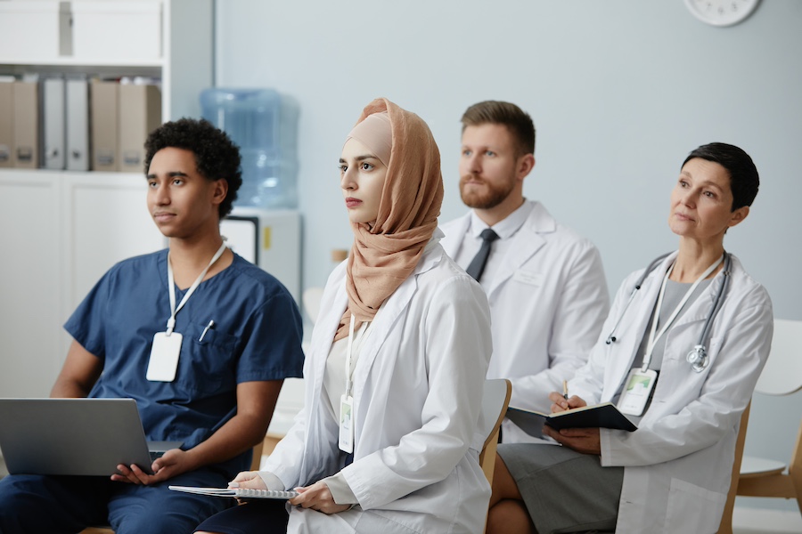 Multiethnic group of doctors sitting in audience at educational seminar and listening to lecture on medicine