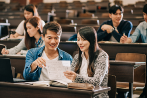 International students studying together in a college lecture hall, discussing coursework.