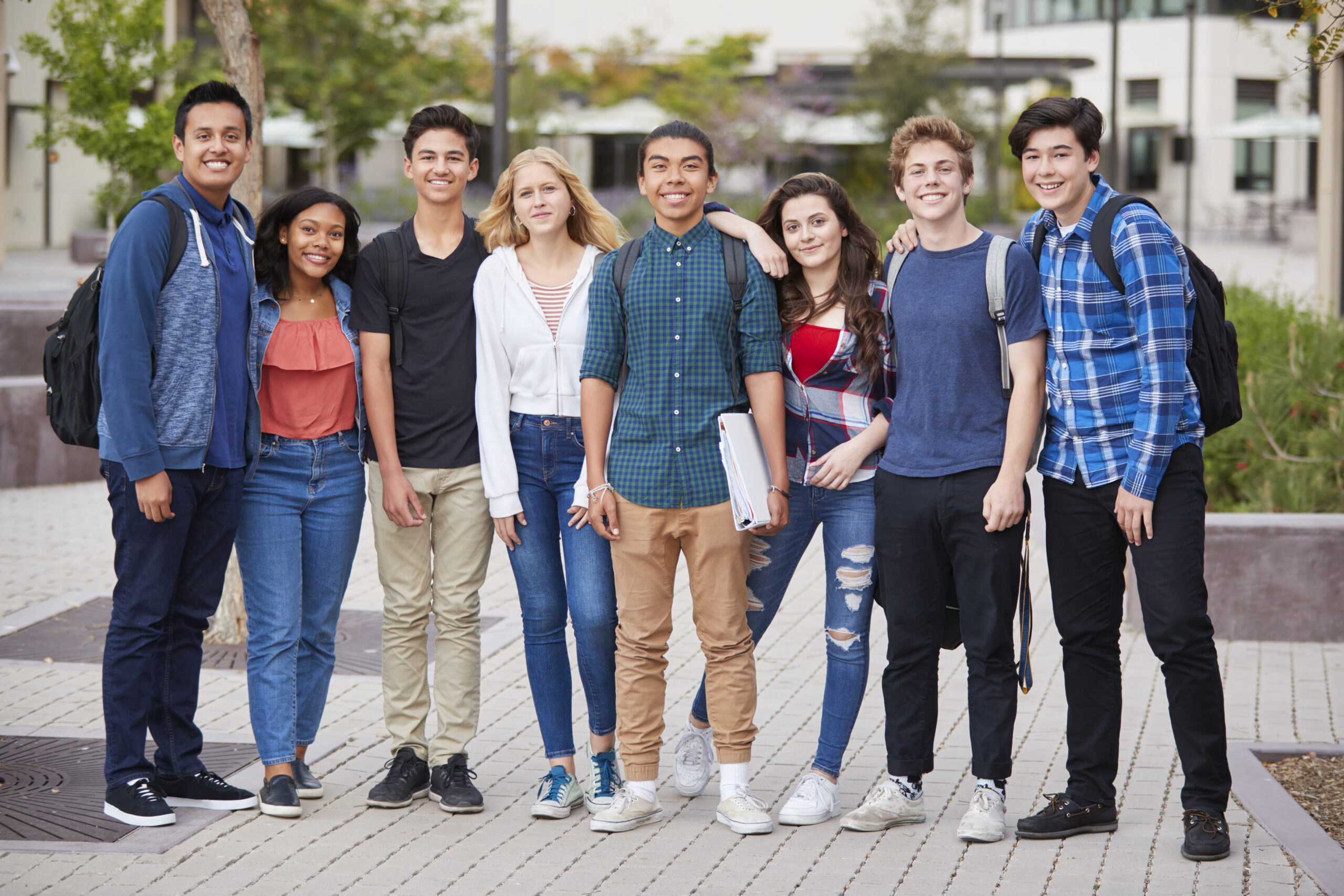High school students standing outside of school with their books.