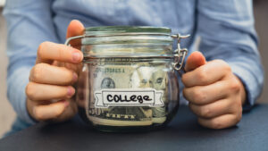 Woman holding a jar with savings money for college.