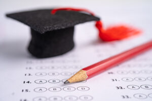 Graduation gap hat and pencil on answer sheet background.