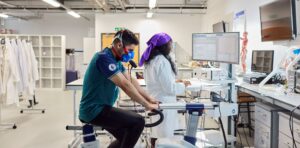 A student participating in a sports science study while researcher takes notes