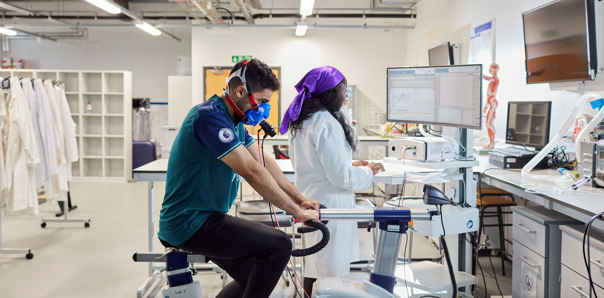 A student participating in a sports science study while researcher takes notes