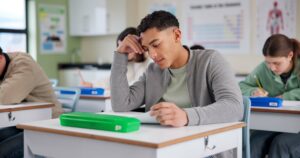 A high school student looking overwhelmed or frustrated with test papers.