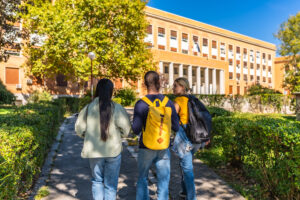 Rear view of three multi-ethnic students walking to the university