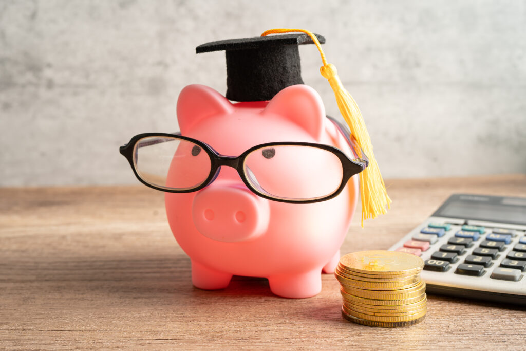 Pigging bank wearing eyeglass with with coins and calculator; saving bank education.