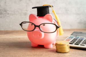 Pigging bank wearing eyeglass with with coins and calculator; saving bank education.