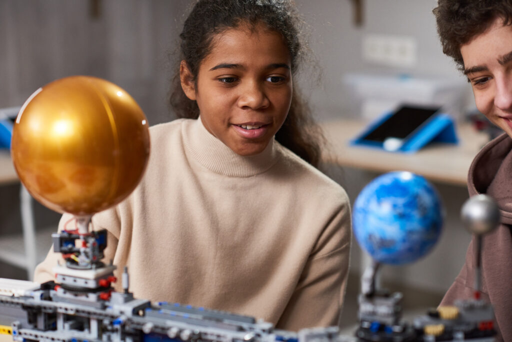 Portrait of black teenage girl building robots while enjoying engineering and robotics class in school